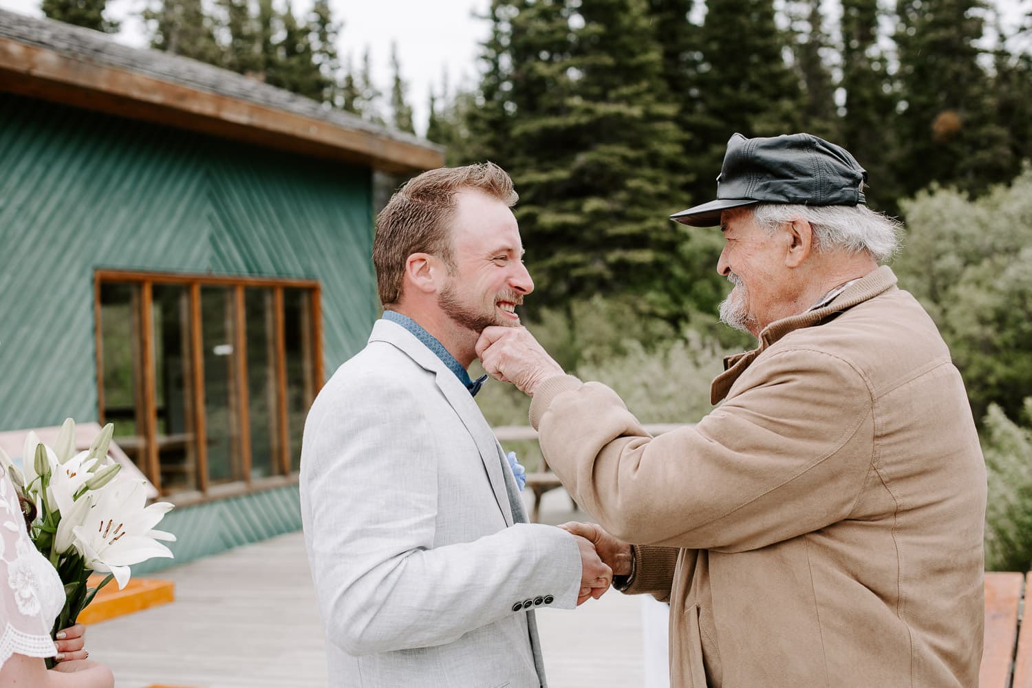a groom being congratulated by his grandfather after the outdoor wedding ceremony. destination wedding photographer.