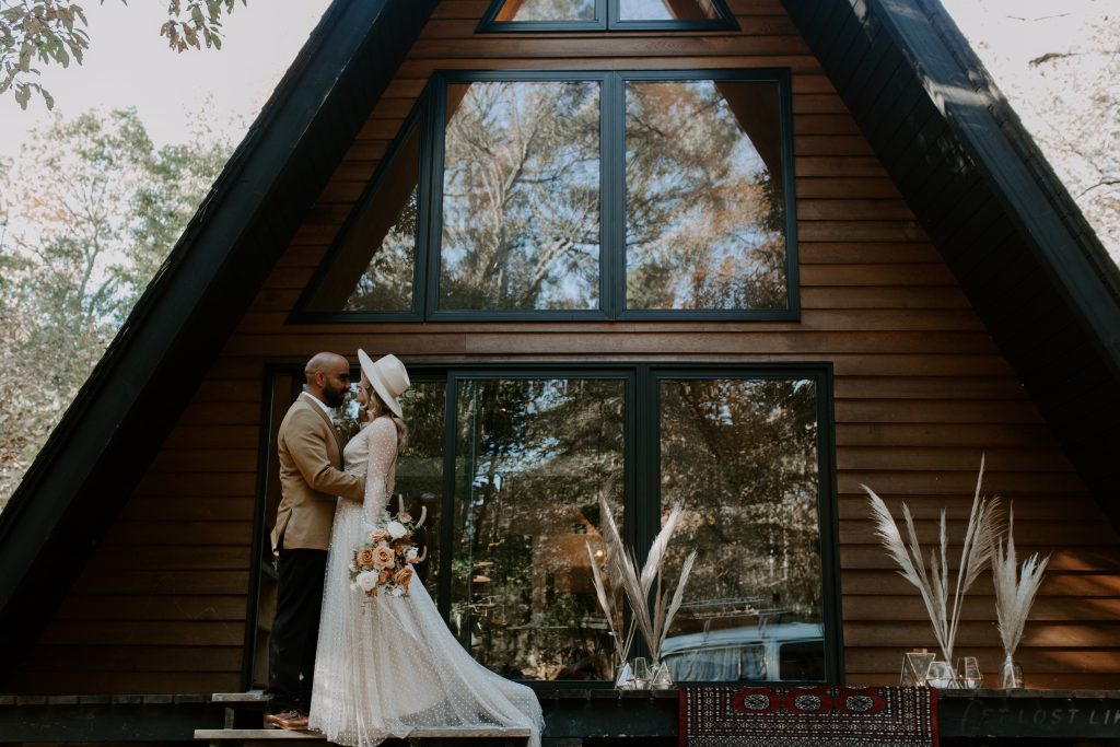 a couple holding each other in front of a cabin in the woods. Ontario elopement photographer