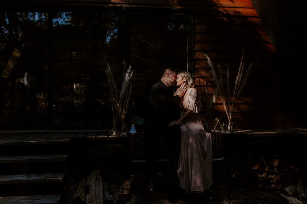 A couple sitting on a cabin porch in the woods. Ontario elopement photographer.