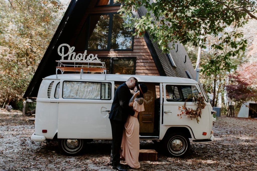 a couple kissing in front of a Photo Booth van and cottage at their elopement. Ontario elopement photographer.