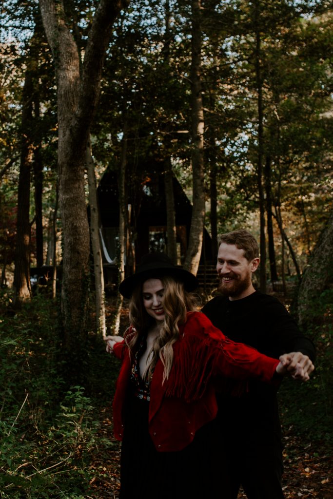 a couple holding hands and smiling in the woods during a couple session. Ontario couple adventure session photographer